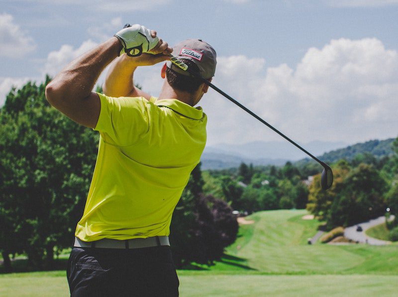 A man in yellow shirt holding golf club.