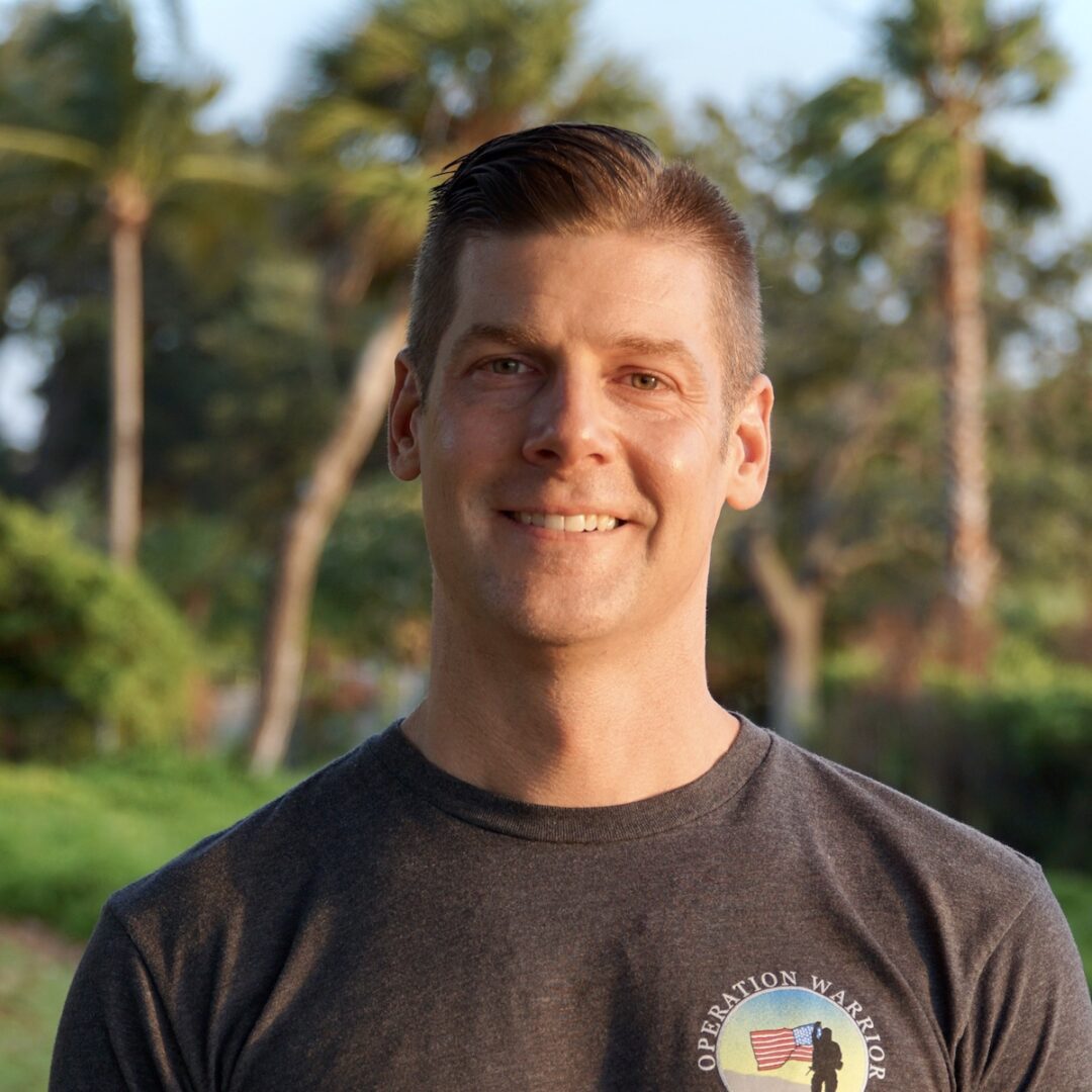 A man in a black shirt standing next to some trees