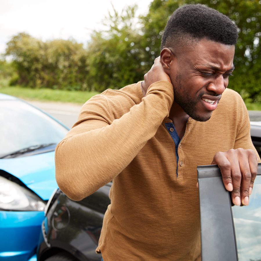 A man holding his neck in pain after an accident.