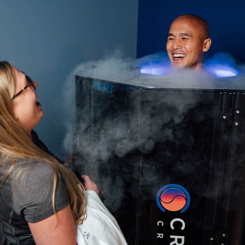 A woman standing next to an ice machine with a man in it.